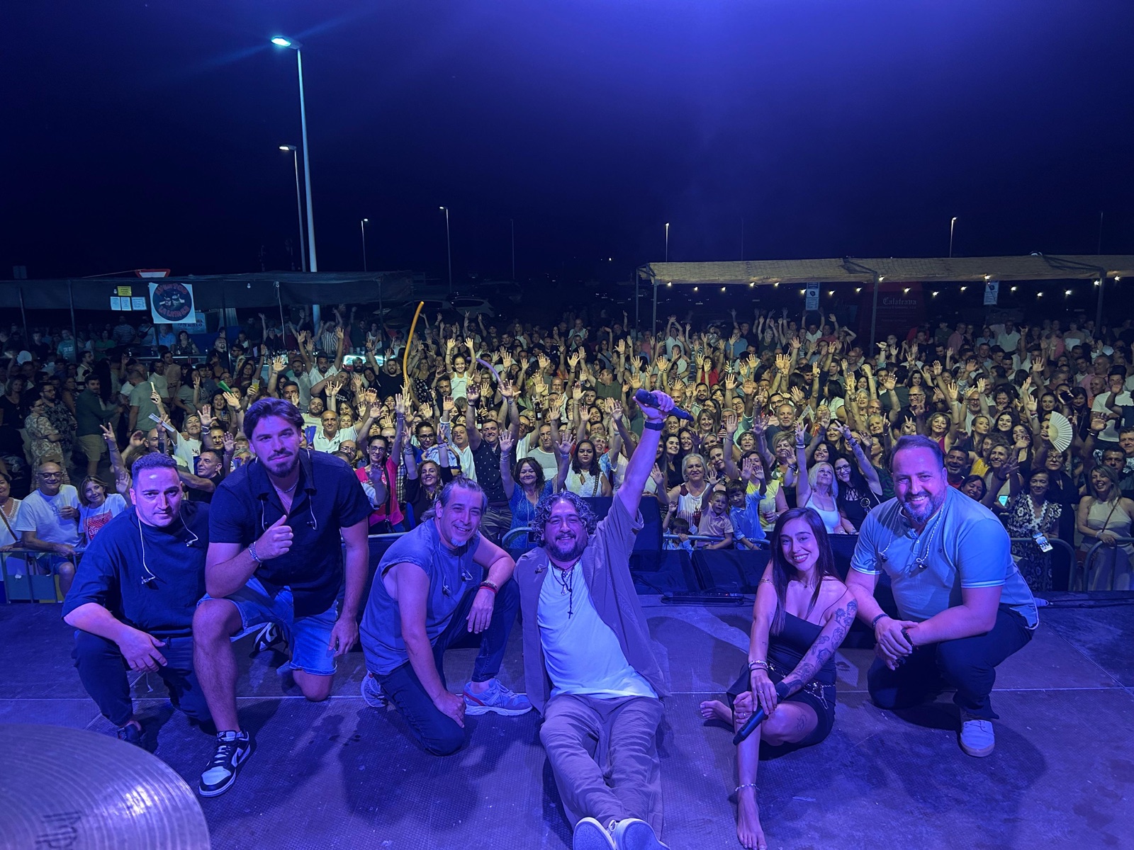 Banda completa de Por Camela en el escenario con la plaza llena de público