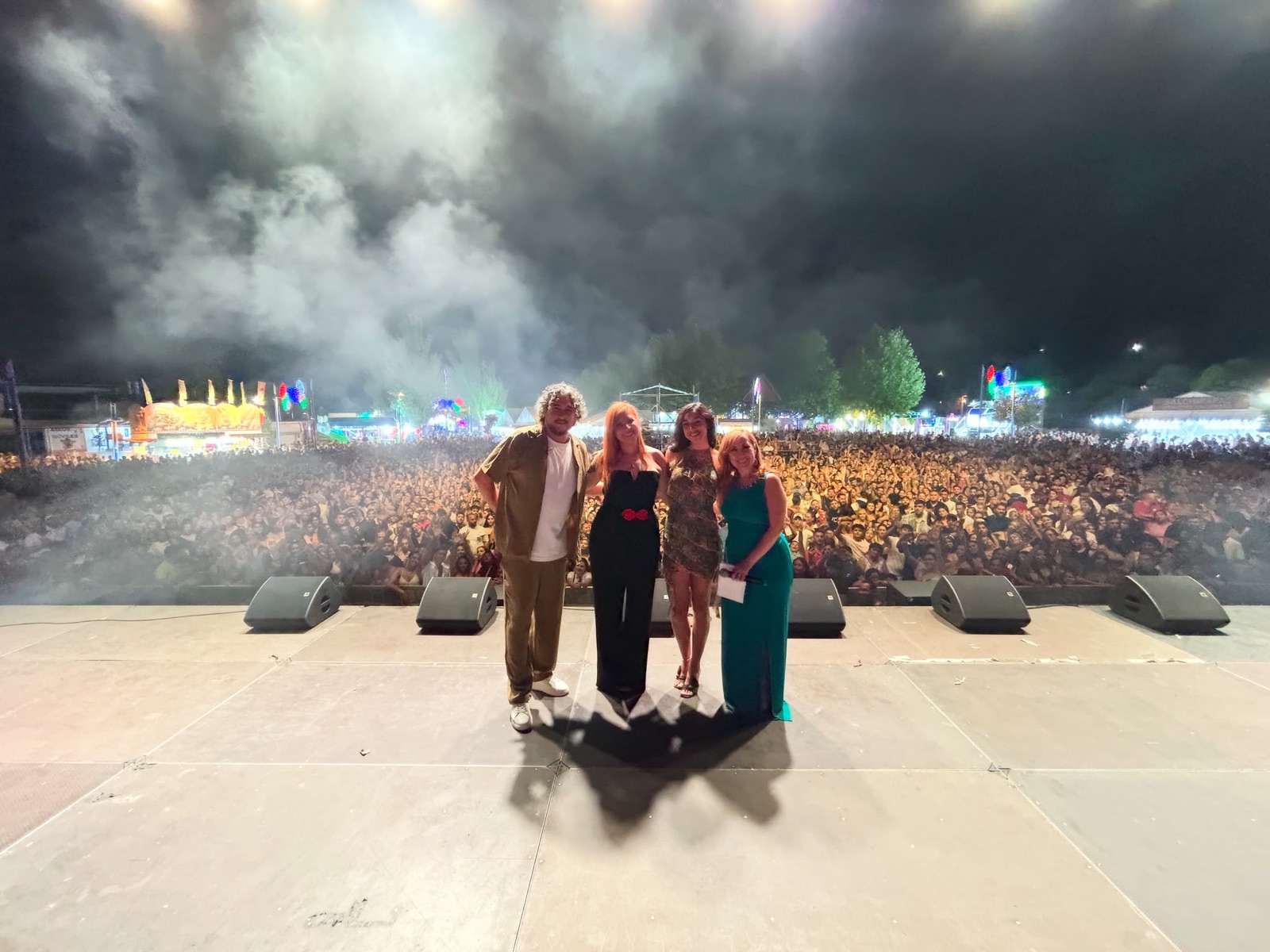 Rubén Martín, Desirée Martínez y el equipo de Por Camela en el escenario con la plaza llena y humo de fiesta